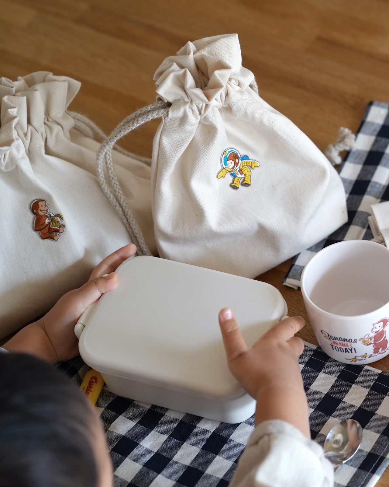 入園準備。無地の巾着袋におさるのジョージのキャラクターワッペンを付けたシンプルなお弁当グッズ